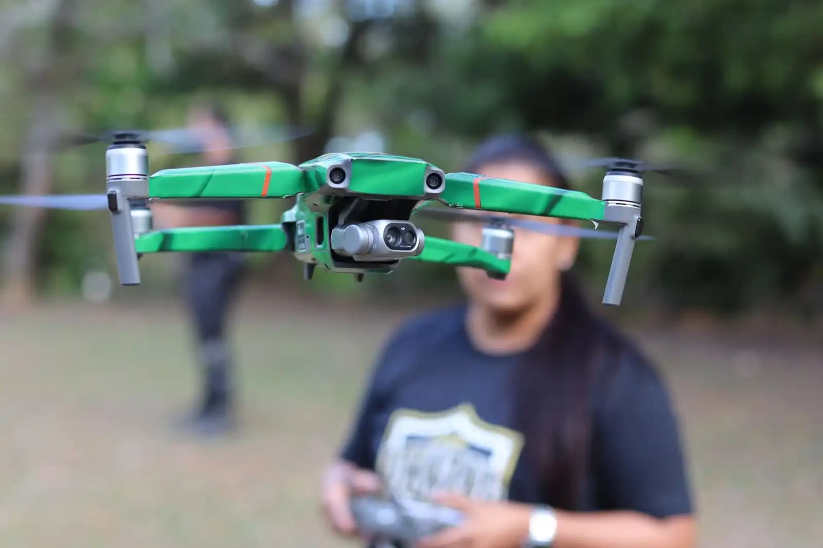 Seorang instruktur drone sedang menjelaskan kepada peserta pelatihan di lapangan terbuka.