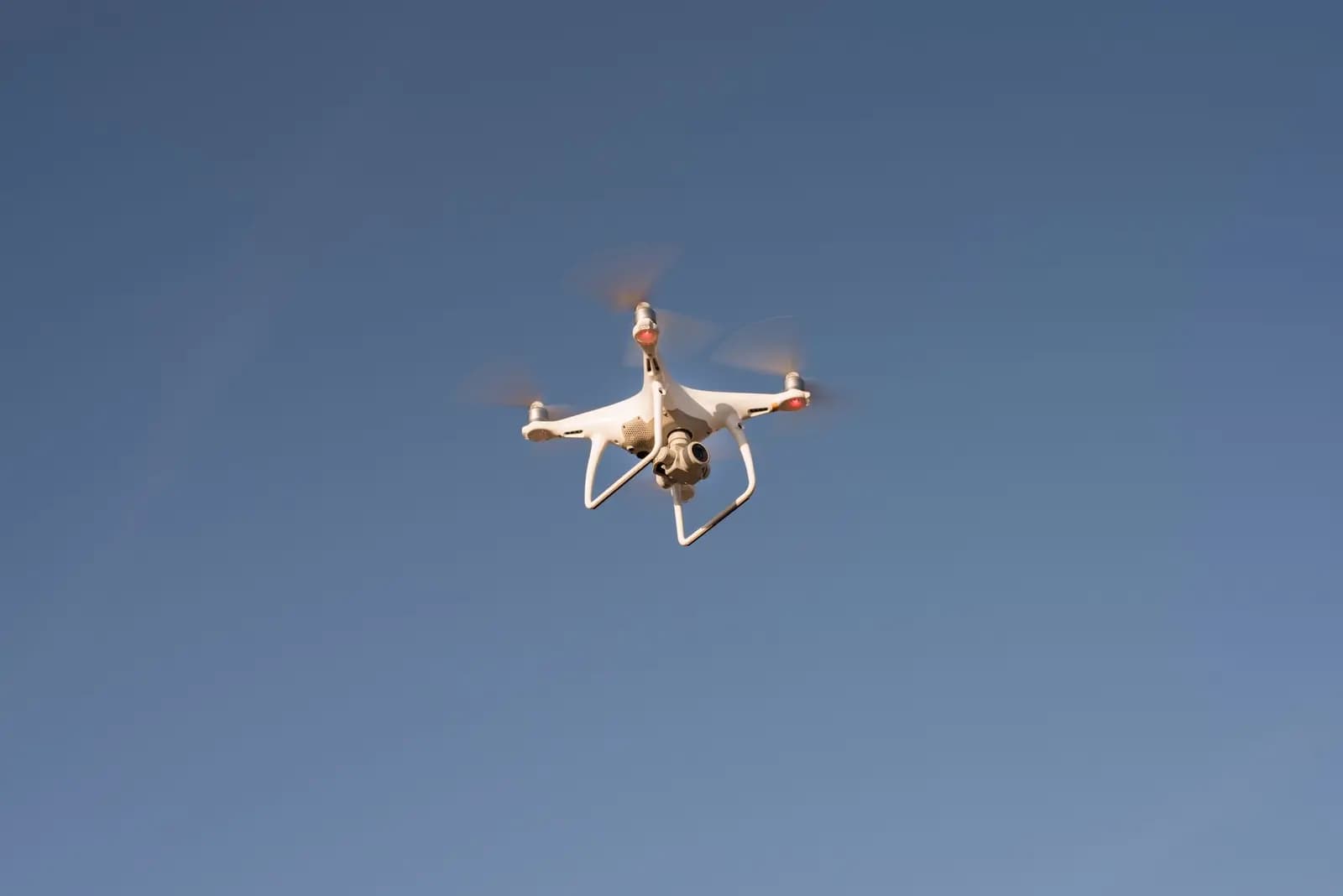 Drone komersial profesional yang sedang turun, menunjukkan efek turbulensi di sekitar baling-baling.