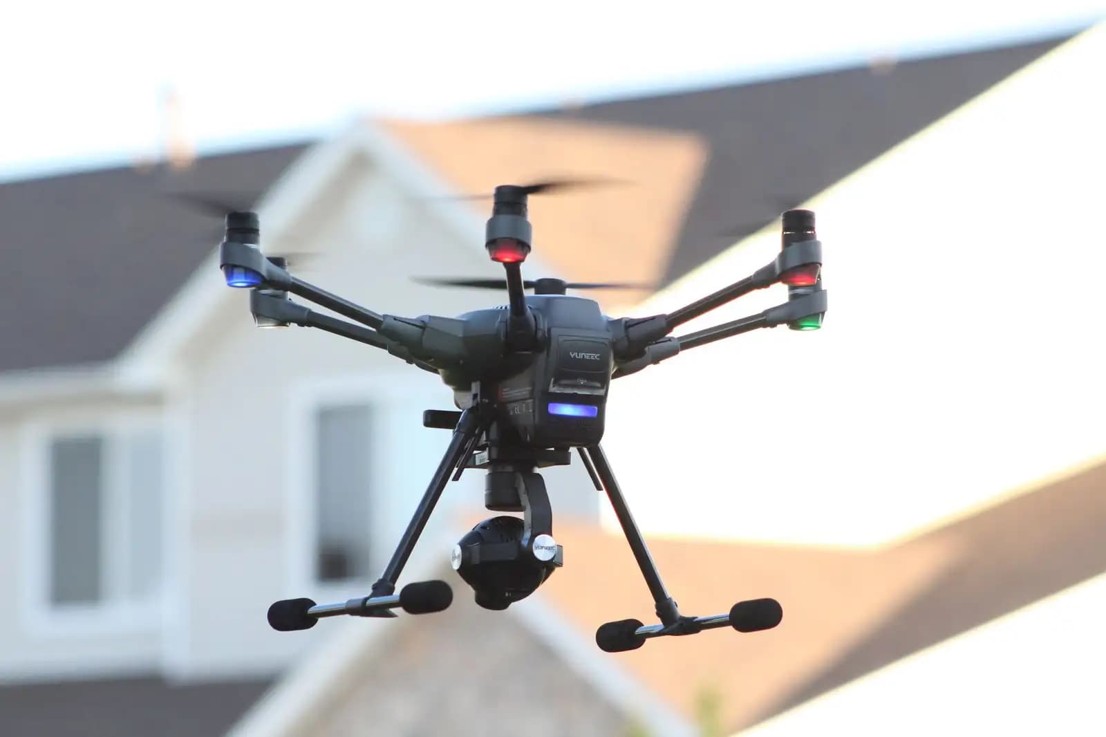 Drone kecil terbang di atas area perumahan, mengawasi dengan kamera
