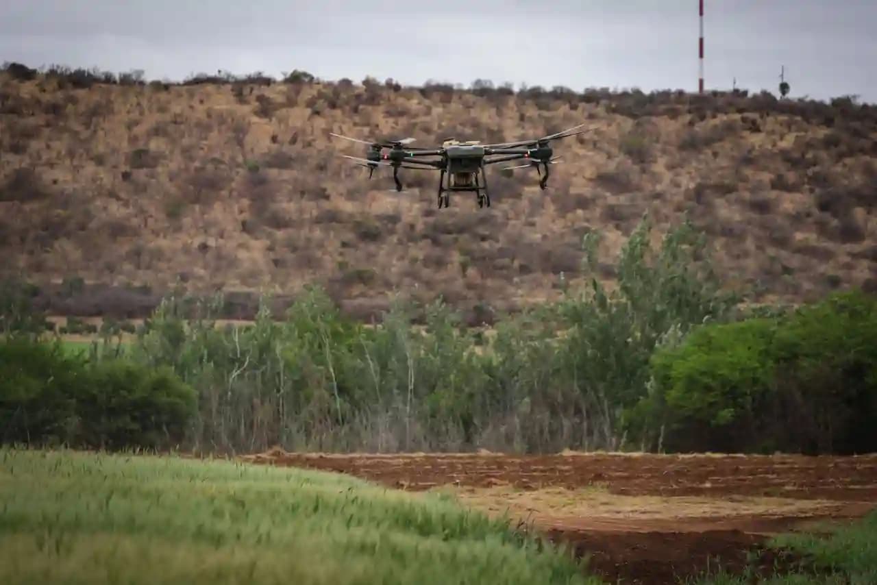 Drone pertanian menyemprotkan cairan di atas lahan hijau yang luas