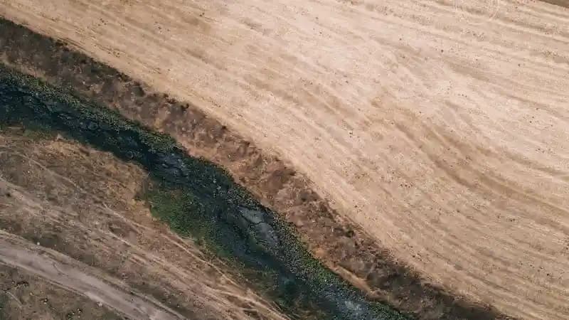 Drone terbang di atas lahan pertanian luas, melakukan survei untuk keperluan perbankan