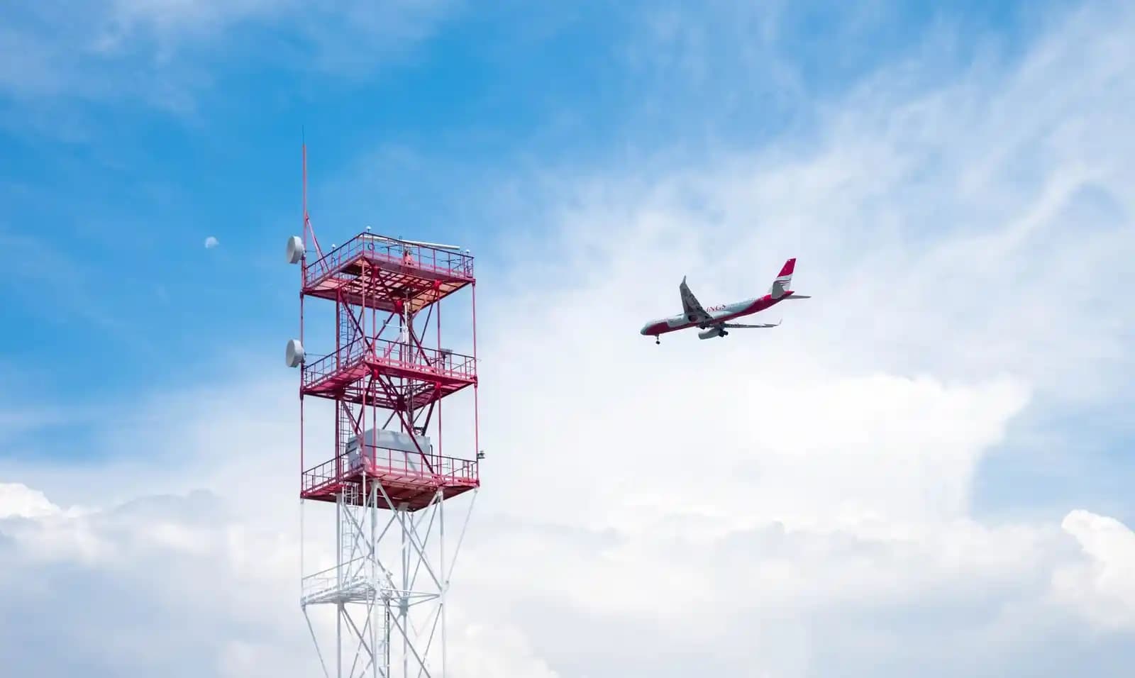 Drone komersial terbang di dekat menara kontrol bandara pada siang hari