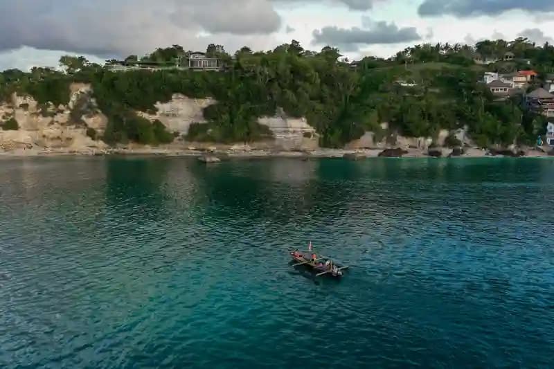 Pilot drone profesional mengoperasikan drone di atas pemandangan pantai Bali yang indah