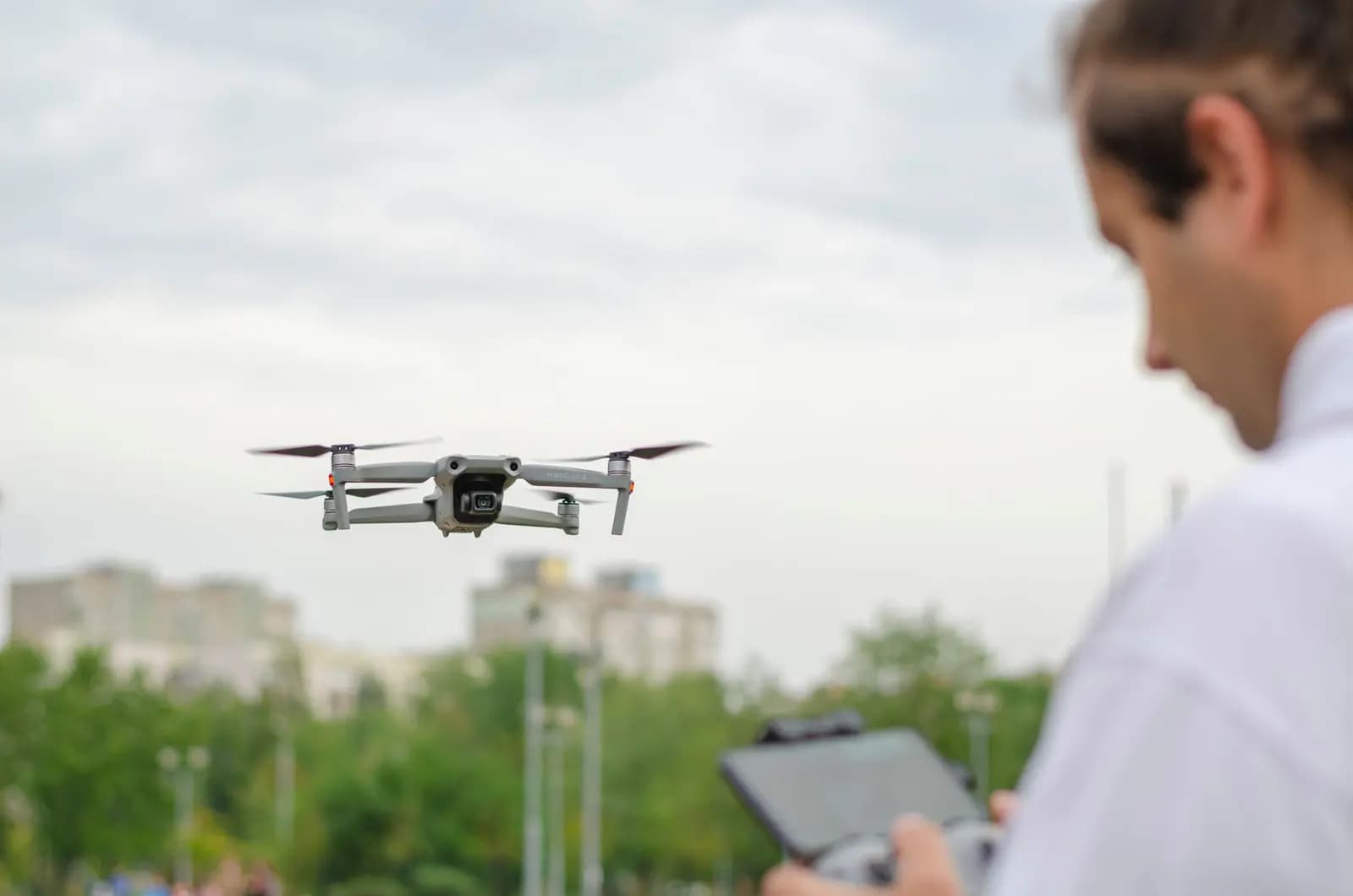 Seorang pilot drone mengoperasikan drone di atas kota Batam dengan latar belakang gedung tinggi.
