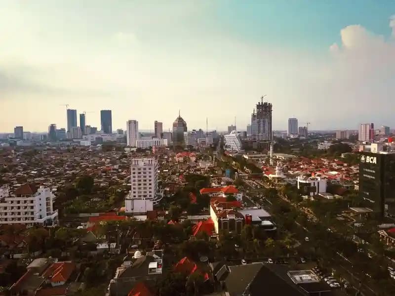 Pilot drone profesional menerbangkan drone di atas lanskap kota Surabaya