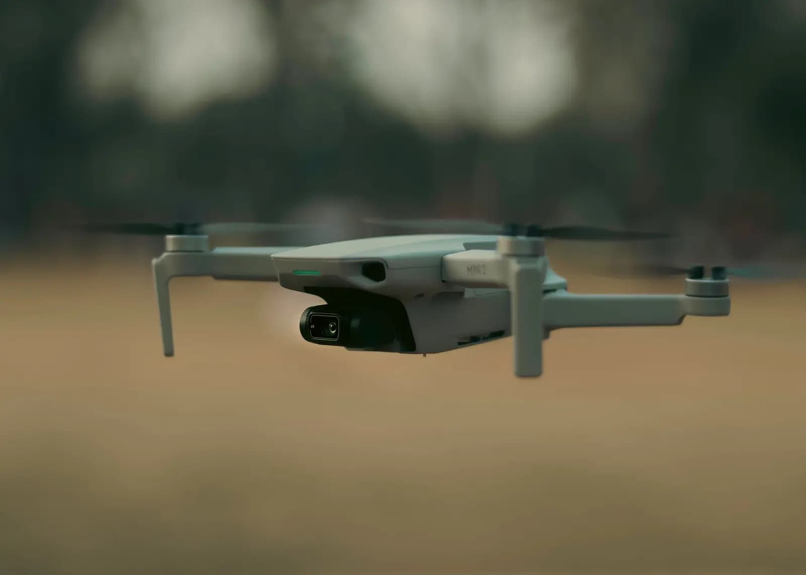 Drone mini terbang di atas taman hijau dengan pilot mengoperasikan dari jauh