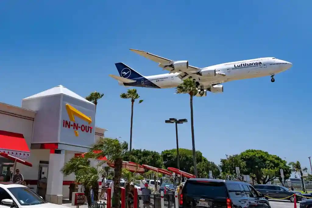 Drone komersial terbang di dekat landasan pacu bandara dengan pesawat di kejauhan