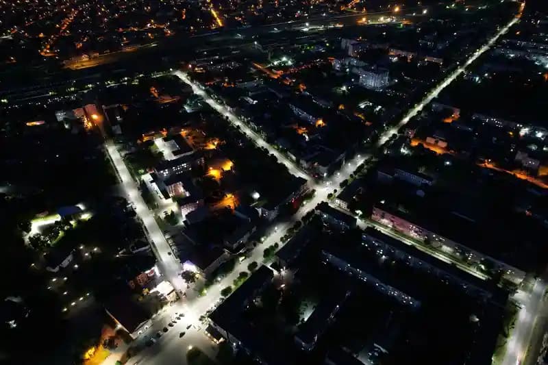 Drone profesional terbang di atas kota pada malam hari dengan lampu menyala