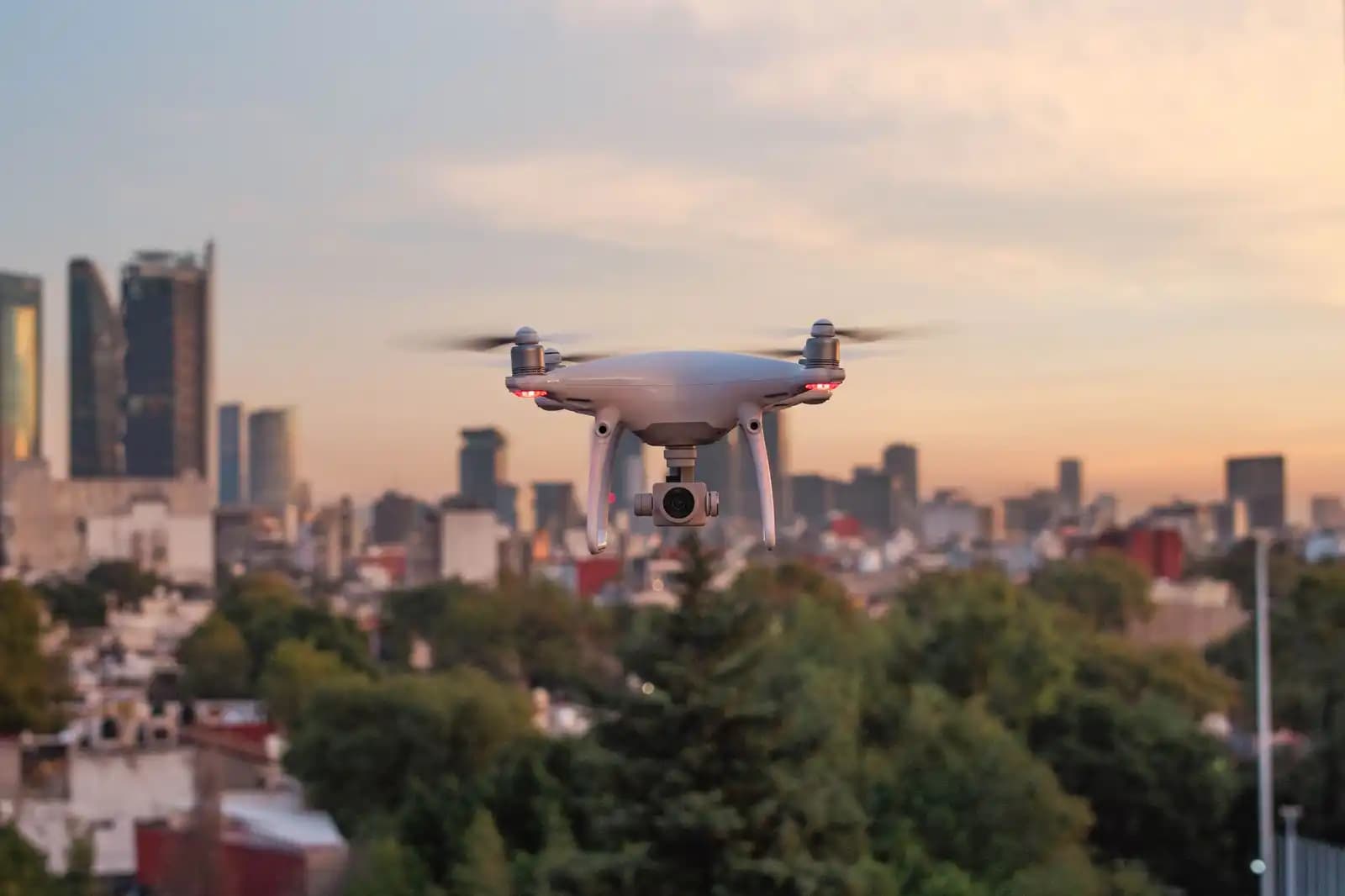 Drone terbang di atas gedung-gedung perkotaan dengan langit biru cerah