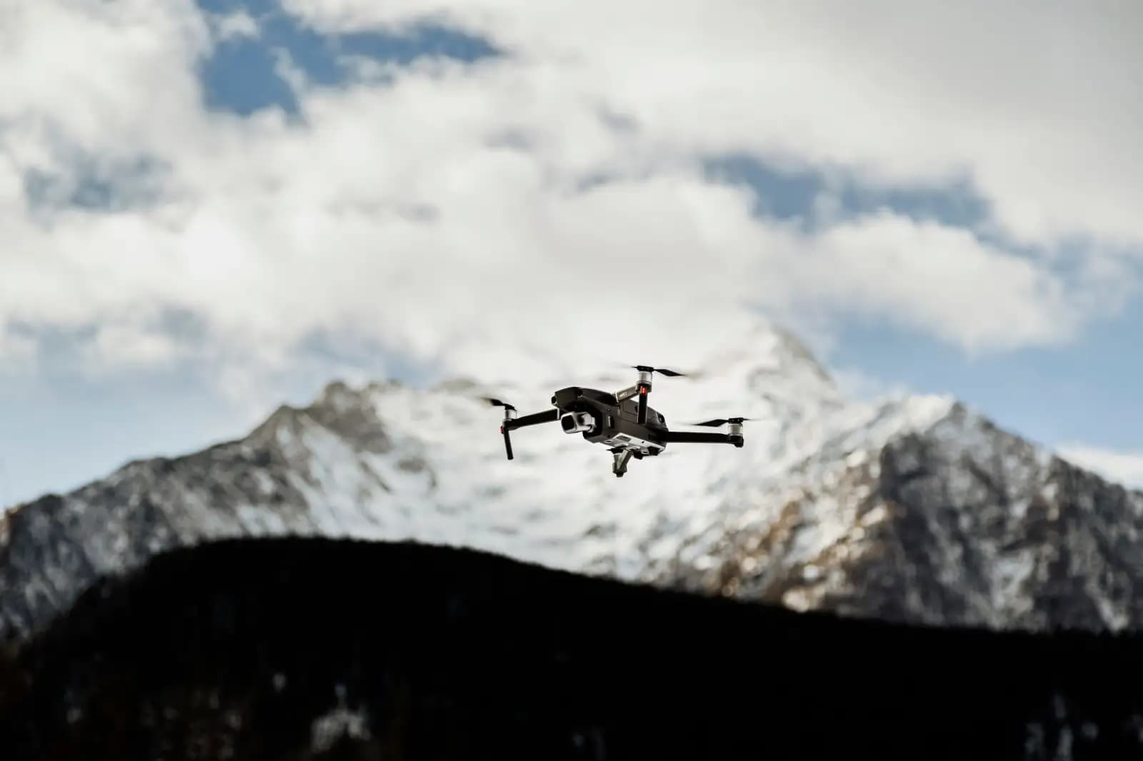 Drone enterprise terbang di pegunungan bersalju dengan latar belakang langit biru