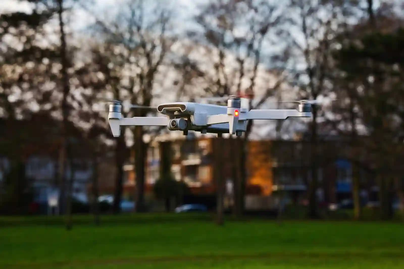 Drone terbang di atas taman kota dengan banyak orang di bawah