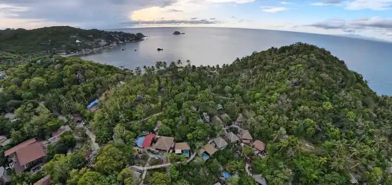 Drone terbang di atas pantai tropis yang indah, menunjukkan potensi pariwisata.