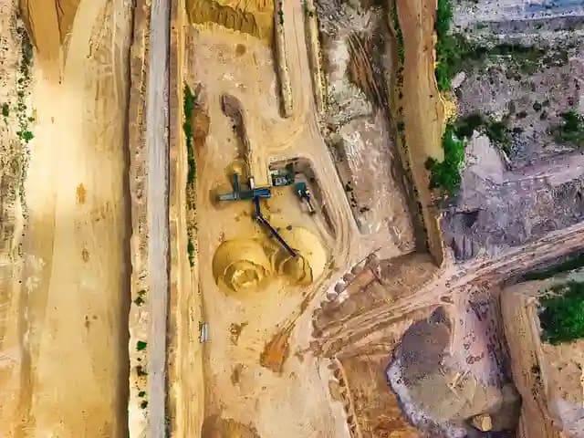 Pilot drone profesional mengoperasikan drone di atas area pertambangan terbuka.