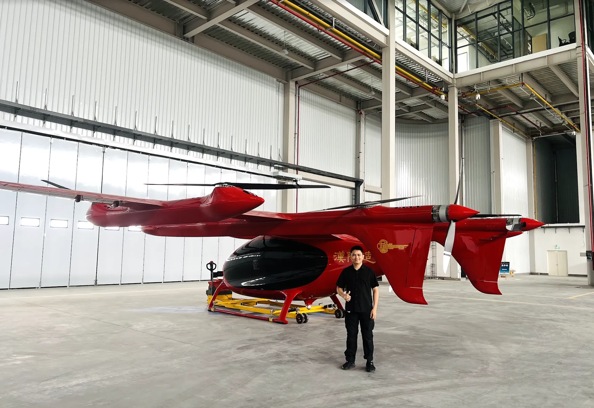 Liu Purnomo berdiri di samping purwarupa eVTOL berwarna merah di fasilitas produksi Hanyang Zao, China