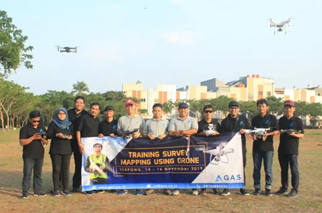 Peserta pelatihan drone berfoto bersama dengan remote controller di lapangan praktik terbang